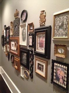 a wall filled with lots of framed pictures on it's side walk next to a stair case