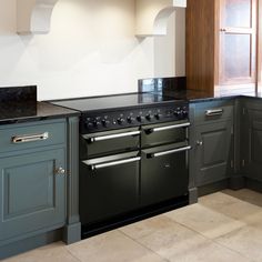 a black stove top oven sitting inside of a kitchen next to green cabinets and counter tops