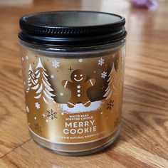 a glass jar filled with christmas cookies on top of a wooden table