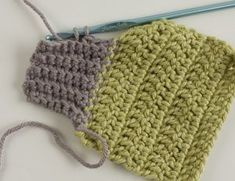 two crocheted items are sitting next to each other on a white surface, one is green and the other is gray