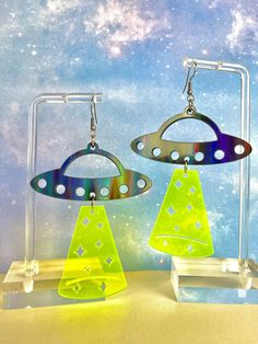 FREE Shipping on orders $35 and up! UFO Beam Earrings These extraterrestrial earrings are carefully handmade with high-quality materials making them durable to last through all your festival adventures! These measure 3 inches long and 2.2 inches wide. - Made with lightweight acrylic for comfortable wear - Earring hooks are stainless steel, nickel-free, and hypoallergenic - Rubber backing included to keep things secure while you dance the night away! Note to Buyer: If you plan to travel with your items please use jewelry boxes. These items may become damaged if stored improperly. Alien Clothes, Weird Earrings, Glowforge Projects, Bay Breeze, Festival Necklace, Fairy Festival, Rave Accessories, Festival Earrings, Hippie Earrings