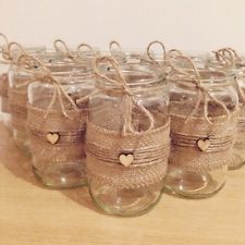 small mason jars with twine and hearts are lined up on a wooden table top