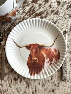 a paper plate with an image of a bull on it and utensils next to it