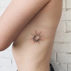 a small sun tattoo on the side of a woman's stomach