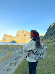 a woman standing on top of a lush green field next to a mountain covered in snow