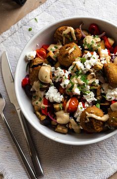 a white bowl filled with food on top of a table next to utensils