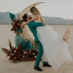 a man and woman hugging each other in front of a moon