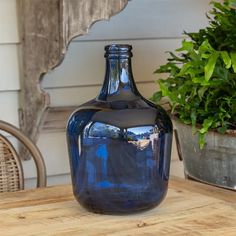 a blue vase sitting on top of a wooden table next to a potted plant