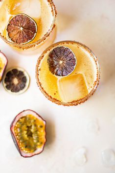 two glasses filled with orange and kiwi fruit on top of a white countertop