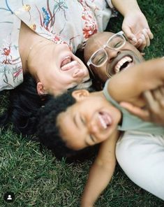 two people laying on the grass with their mouths open