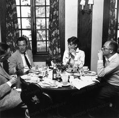 black and white photograph of people sitting around a table with food in front of them