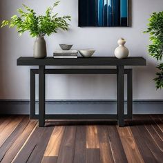 two vases are sitting on a table in front of a painting that is hanging on the wall