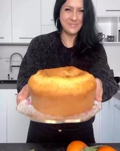 a woman holding a cake on top of a counter next to an orange and white plate