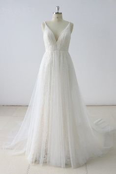 a white wedding dress on a mannequin stand in front of a white wall