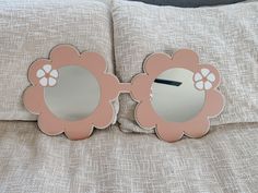 a pink flower shaped mirror sitting on top of a bed next to two pillow cases