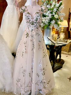 wedding gowns on display in a bridal shop with white flowers and greenery