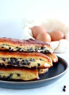 three pancakes on a plate with blueberries and an egg in the backround