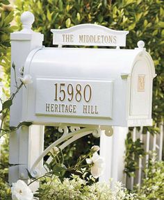 a white mailbox sitting in the middle of some bushes