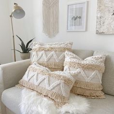 some pillows are on a couch in a room with white walls and pictures above them