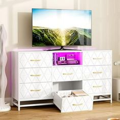 a flat screen tv sitting on top of a white dresser