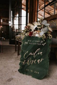 the welcome sign is decorated with greenery and gold lettering for an elegant winter wedding