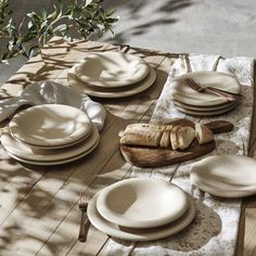 the table is set with plates and utensils on it, along with bread