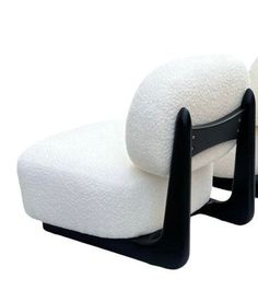 two white chairs with black legs and one has a pillow on it's back