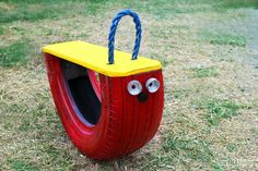 a red tire swing with eyes and nose on it's side in the grass