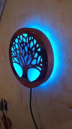 a blue light that is on the side of a wall next to a clock with a tree