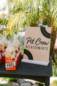 a table topped with red boxes filled with popcorn next to a sign that says pit crew refreshments