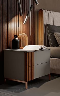 a nightstand with a book, vase and lamp on it