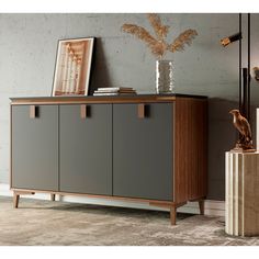 a sideboard with two doors and some pictures on the wall behind it in a living room