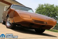 an orange muscle car parked in front of a garage with the words mopar connection on it