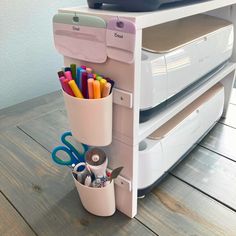 a stack of office supplies sitting on top of a wooden table next to a printer