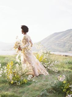 a woman in a dress is walking through the grass