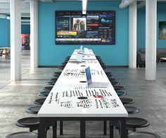 a long table is set up in the middle of a room with blue walls and black chairs