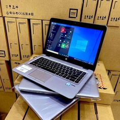 an open laptop computer sitting on top of a pile of boxes