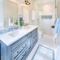 a white bathroom with blue accents and tile flooring, along with a walk in shower