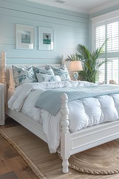 a white bed sitting in a bedroom on top of a wooden floor next to a window