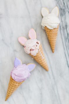 three ice cream cones with bunny ears on them and one has pink frosting in it