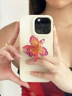 a woman holding up her phone case with an image of a flower on it