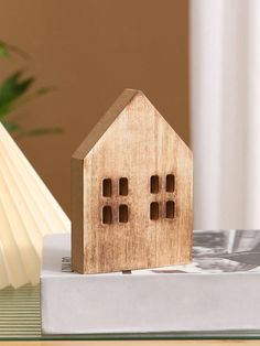 a small wooden house sitting on top of a book