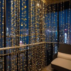 a living room filled with furniture and lots of gold beads hanging from the ceiling next to a window