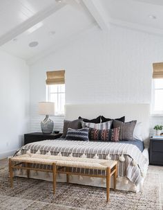 a bedroom with white brick walls and wood trim on the ceiling is decorated in neutral tones