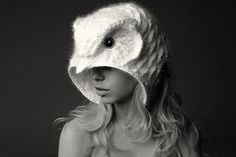 a woman wearing a white knitted hat with an owl's head on it