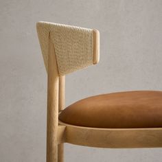 a wooden chair with a brown cushion on it's seat and back rests against a wall