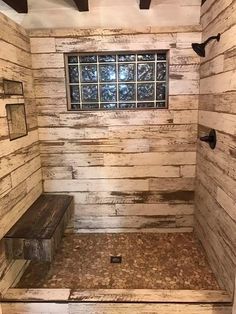 a bathroom with wooden walls and flooring next to a window on the wall is a bench