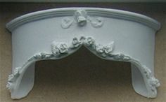 an ornate white headboard with flowers and leaves on the top, is shown in front of a beige wall