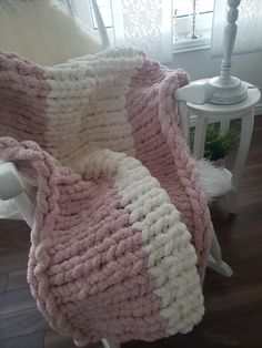 a pink and white blanket sitting on top of a chair