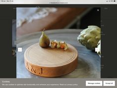 a wooden cutting board sitting on top of a metal table next to a piece of artichoke